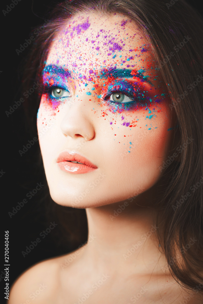 Portrait of a young beautiful blue-eyed brunette woman with a spray of eyeshadow