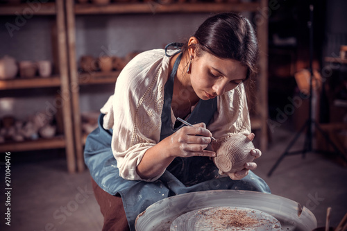 Charming ceramist girl is working on pottery wheel. Handmade. photo