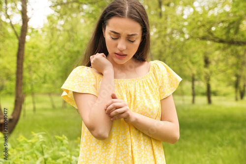 Young woman scratching hand outdoors. Seasonal allergy photo