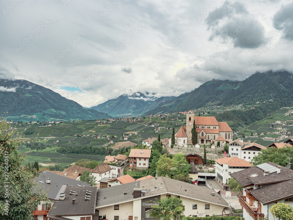 general view of an alpine valley with old town and church surrounded by mountains