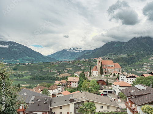 general view of an alpine valley with old town and church surrounded by mountains