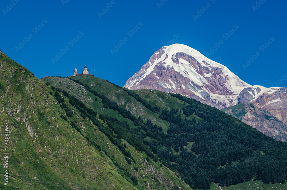 Obraz premium Kazbek Mountain in Caucasus Mountains, Georgia. View with one of the foremost Georgian landmarks - Tsminda Sameba church