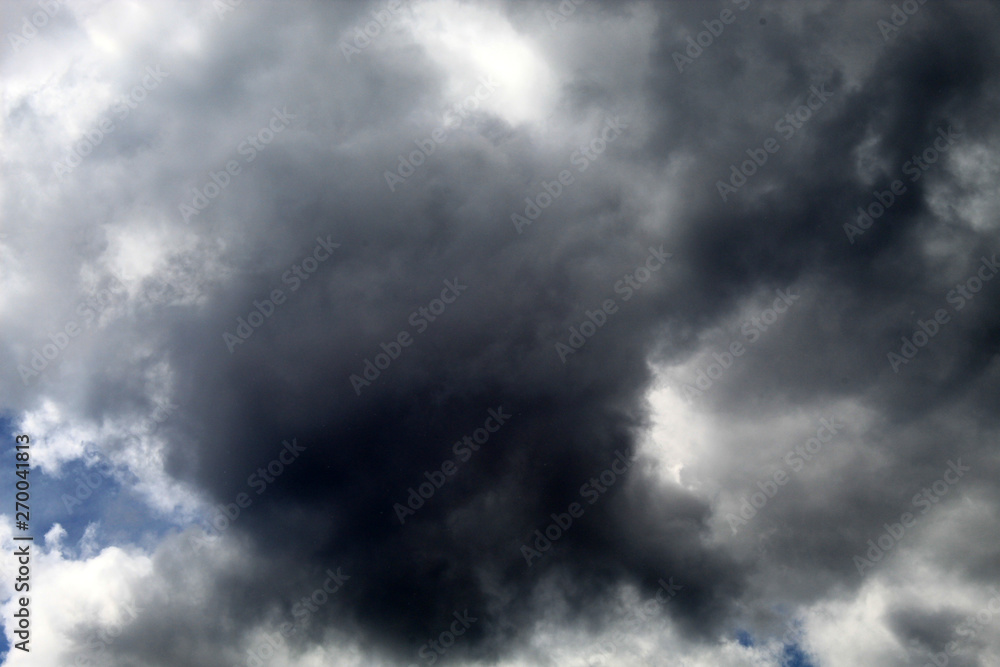 Menacing dark gray cloud covered the sun and blue sky