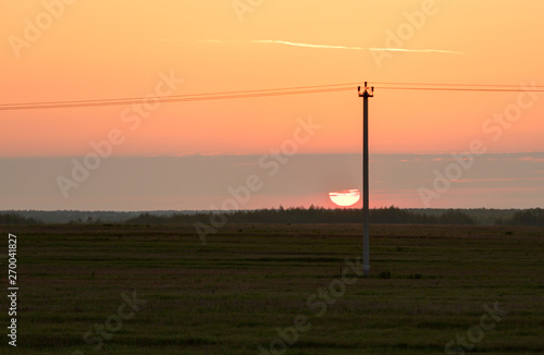 Sunset with orange sky. Telegraph pole against the sun.