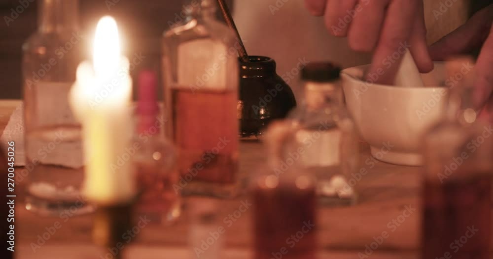 Scene tracks right across medicinal bottles in the foreground with focus on a pharmacist or alchemist in background working with a mortar and pestle. Scene tracks right across medicinal bottles in the foreground with focus on a pharmacist or alchemist in background working with a mortar and pestle.