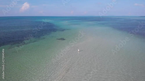 Tourist girl walking on a white sandbar above the crystal clear water at Punta Sebaring in Balabac, drone shot in Palawan, Philippines photo