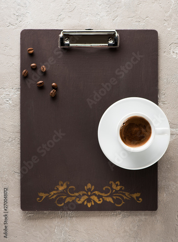 Cup coffee with coffee beans on a vintage empty clipboard and space for menu text.