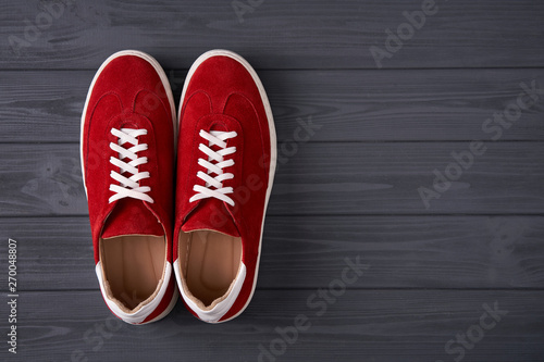Top view of casual red suede trainers on grey wooden planks