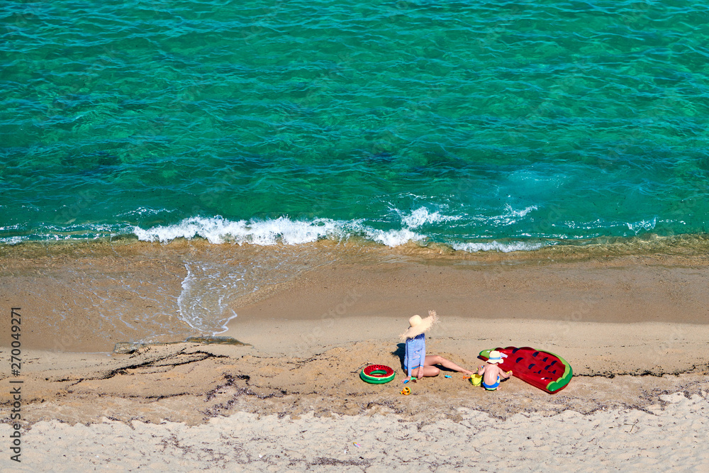 Two year old toddler boy and his mother on beach with inflatable float and ring. Summer family vacation. Sithonia, Greece. Two year old toddler boy and his mother on beach with inflatable float and ring. Summer family vacation. Sithonia, Greece.