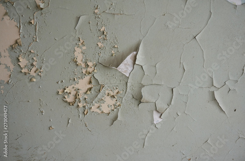 Old wall: chipped, partially peeled-off white, beige and green paint. 