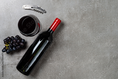 Wine bottle, glass, opener and grapes on concrete background. Copy Space.