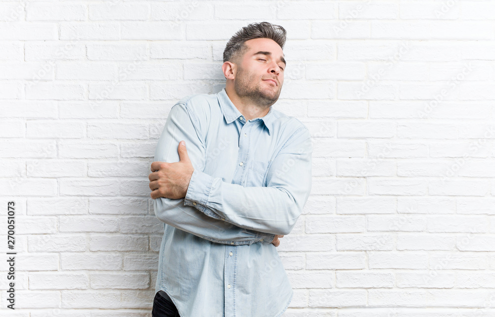 Young handsome man against a bricks wall hugs, smiling carefree and happy. Young handsome man against a bricks wall hugs, smiling carefree and happy.