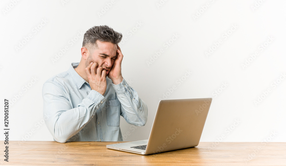 Young handsome man working with his laptop whining and crying disconsolately. Young handsome man working with his laptop whining and crying disconsolately.