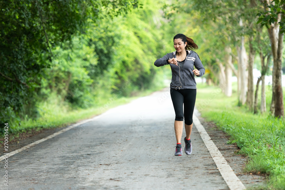 Running woman. Sport Women jogging during and check timing. Outdoor Workout in a Park. Weight Loss and Healthy Concept Running woman. Sport Women jogging during and check timing. Outdoor Workout in a Park. Weight Loss and Healthy Concept