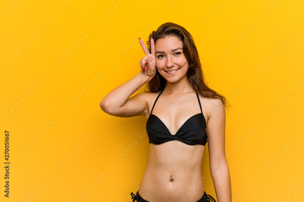 Young european woman wearing bikini showing victory sign and smiling broadly. Young european woman wearing bikini showing victory sign and smiling broadly.