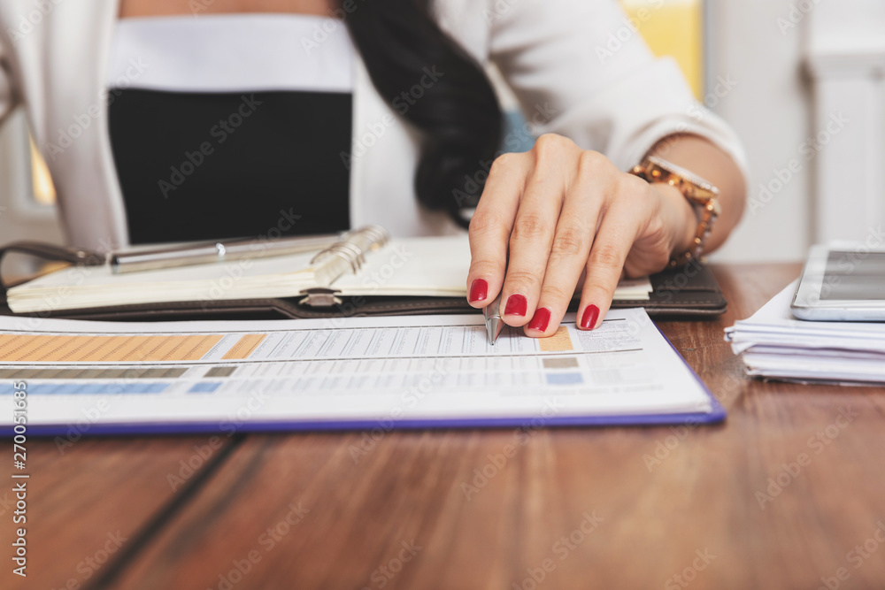 Closeup of woman's hand holding a pen on notebook. Freelance journalist working at home. Closeup of woman's hand holding a pen on notebook. Freelance journalist working at home.