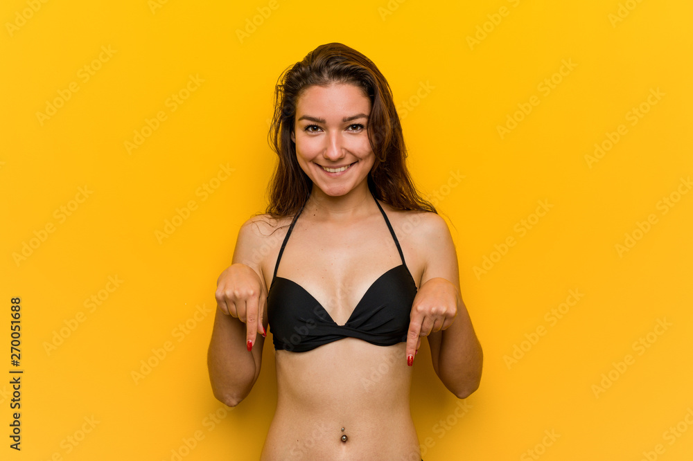 Young european woman wearing bikini points down with fingers, positive feeling. Young european woman wearing bikini points down with fingers, positive feeling.