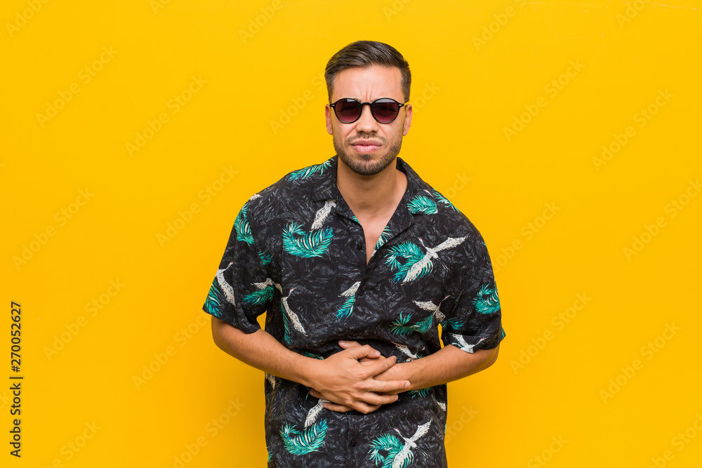 Young filipino man wearing summer clothes sick, suffering from stomachache, painful disease concept.