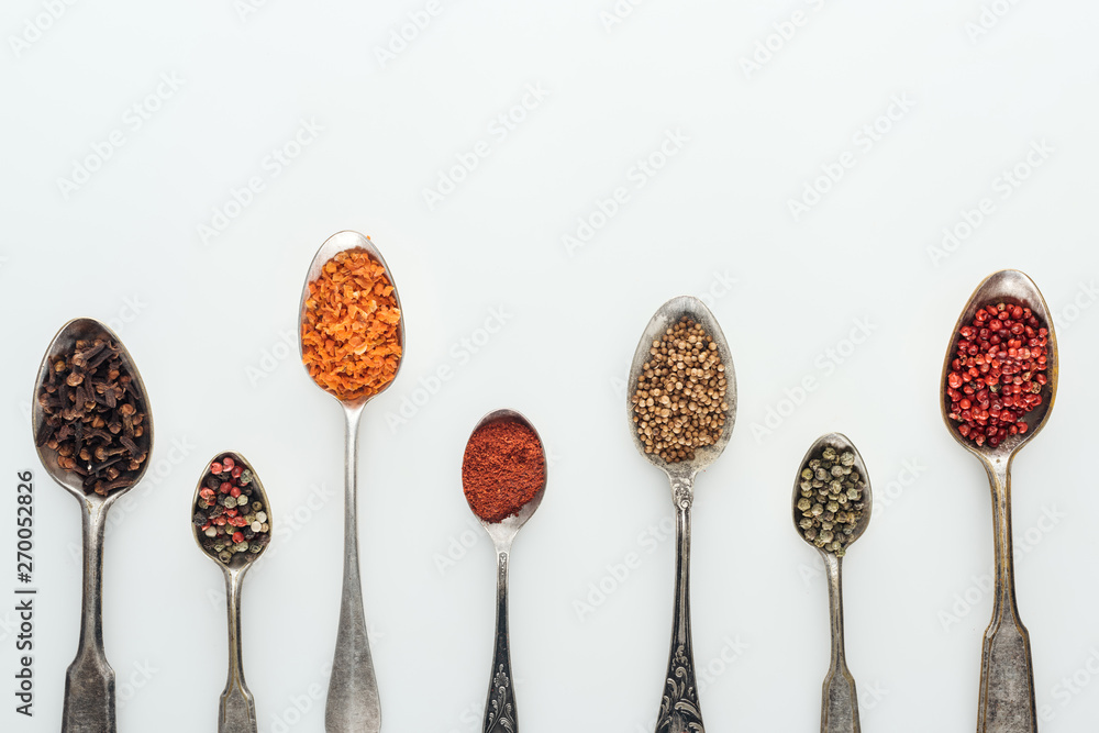top view of colorful spices in silver spoons on white background with copy space - obrazy, fototapety, plakaty 