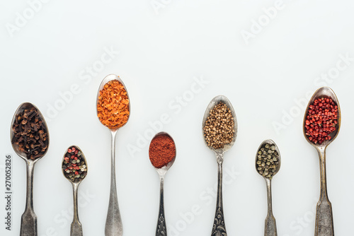 Fototapeta Naklejka Na Ścianę i Meble -  top view of colorful spices in silver spoons on white background with copy space