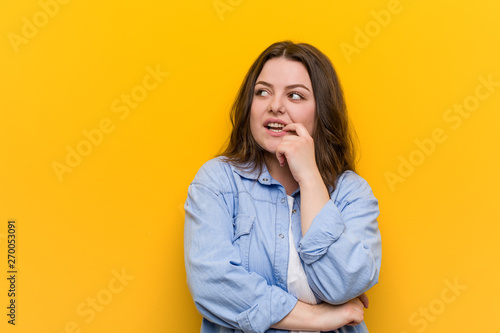 Young curvy plus size woman relaxed thinking about something looking at a copy space. © Asier