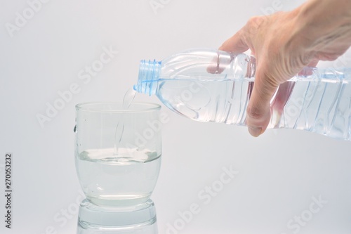 Botella de mano llenando un vaso de agua