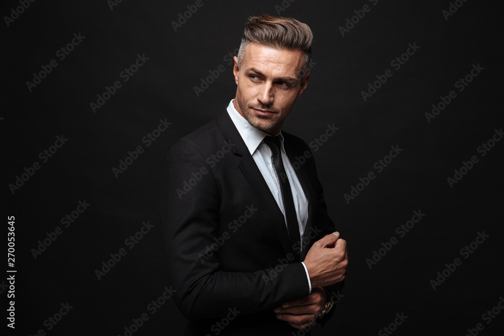 Portrait of european unshaved businessman dressed in formal suit posing and looking aside - obrazy, fototapety, plakaty 