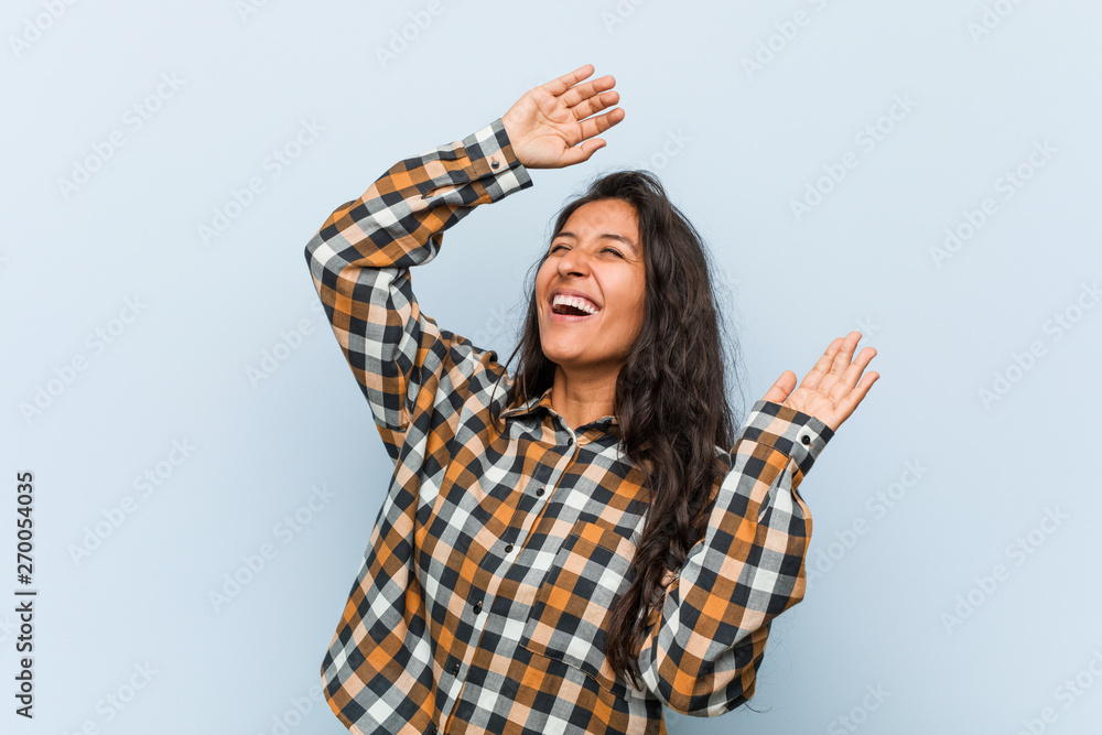 Young cool indian woman celebrating a special day, jumps and raising arms with energy. Young cool indian woman celebrating a special day, jumps and raising arms with energy.