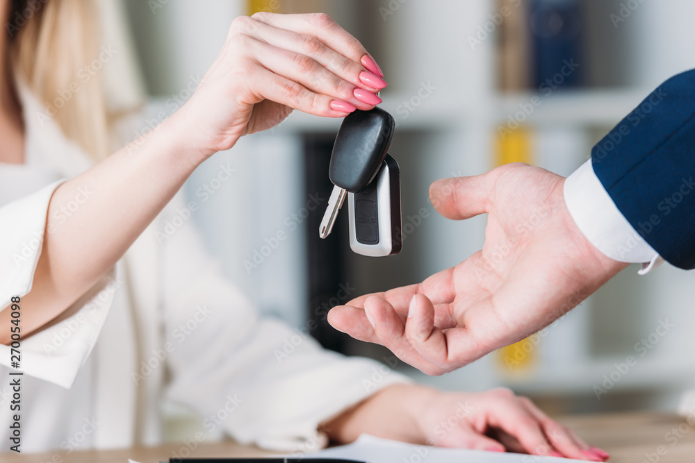 cropped shot of woman taking car keys from car dealer in office