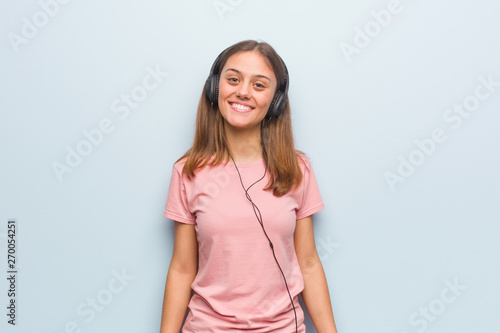 Young pretty caucasian woman cheerful with a big smile. She is listening to music with headphones. © Asier
