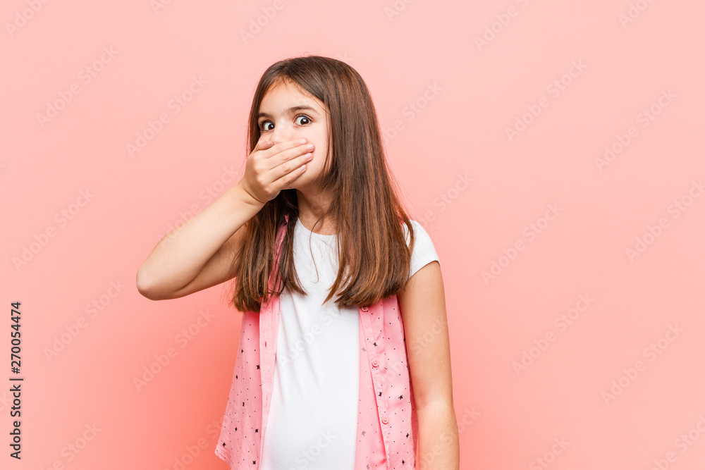 Cute little girl thoughtful looking to a copy space covering mouth with hand. Cute little girl thoughtful looking to a copy space covering mouth with hand.