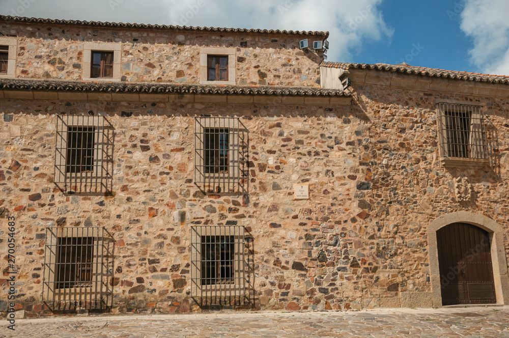 Medieval building facade, with wooden door and barred windows at Caceres