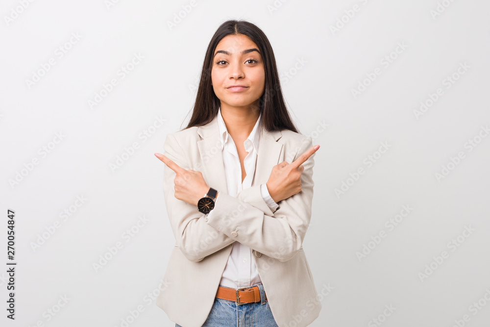 Young business arab woman isolated against a white background points sideways, is trying to choose between two options. Young business arab woman isolated against a white background points sideways, is trying to choose between two options.