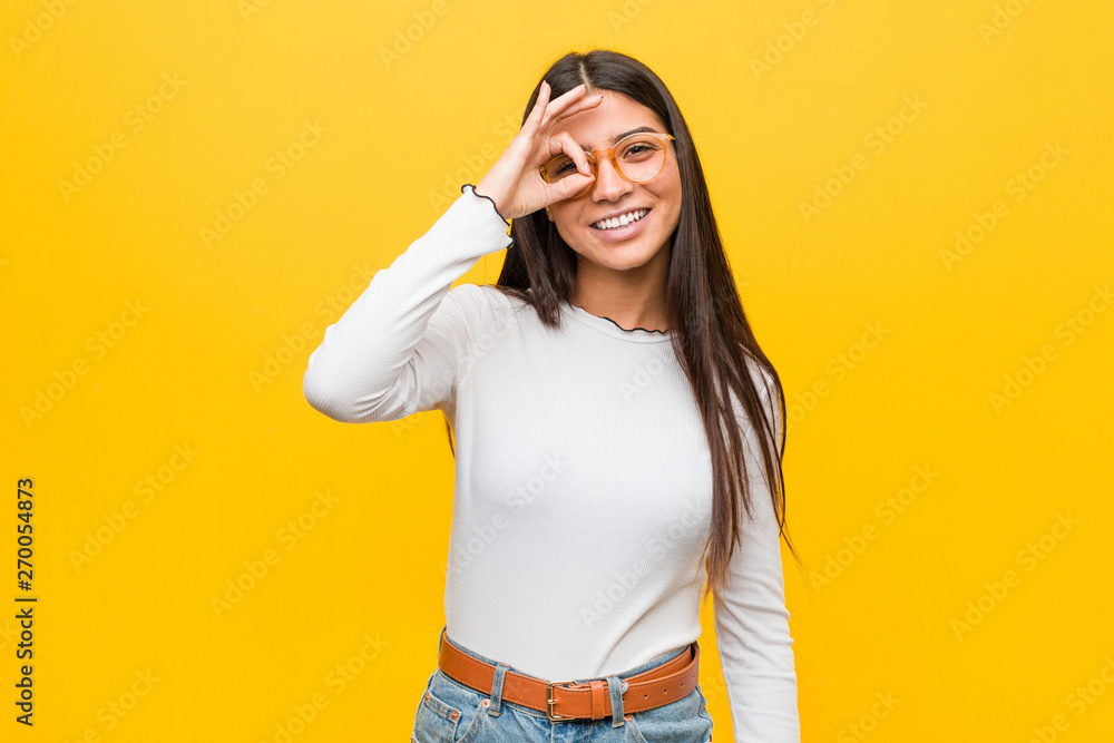 Young pretty arab woman against a yellow background excited keeping ok gesture on eye. Young pretty arab woman against a yellow background excited keeping ok gesture on eye.