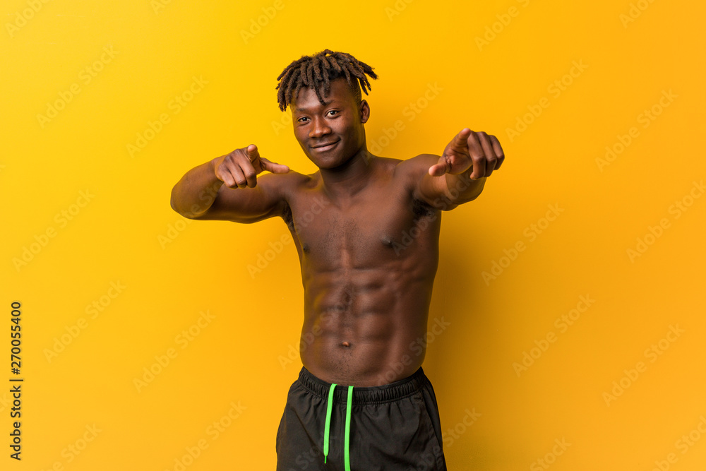 Young black man shirtless wearing swimsuit cheerful smiles pointing to front. Young black man shirtless wearing swimsuit cheerful smiles pointing to front.