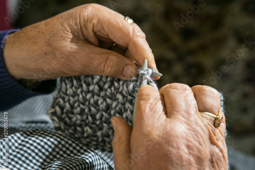 Retired elderly woman weaves woolen clothes with her hands