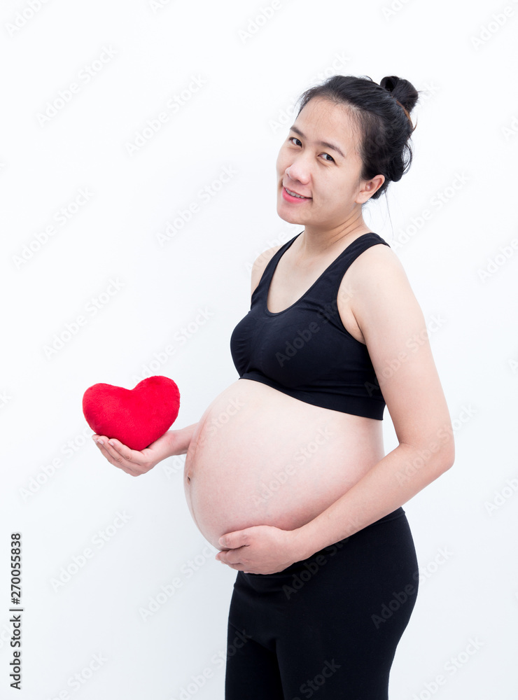 Young beautiful Asian pregnant woman touching her belly at home