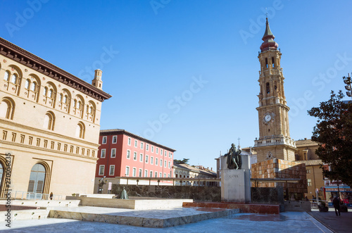 Zaragoza, Aragon, Spain - February 14th, 2019 : Bell tower of La Seo cathedral of the Savior and Francisco de Goya monument at the Plaza del Pilar square.