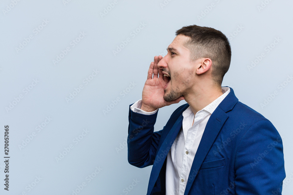 Young business caucasian man shouting and holding palm near opened mouth. Young business caucasian man shouting and holding palm near opened mouth.