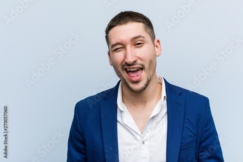 Young business caucasian man winking, funny, friendly and carefree.