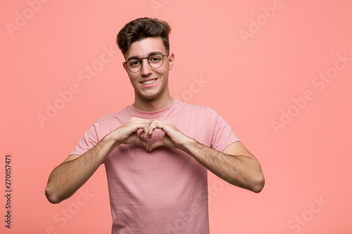 Young cool caucasian man smiling and showing a heart shape with him hands.