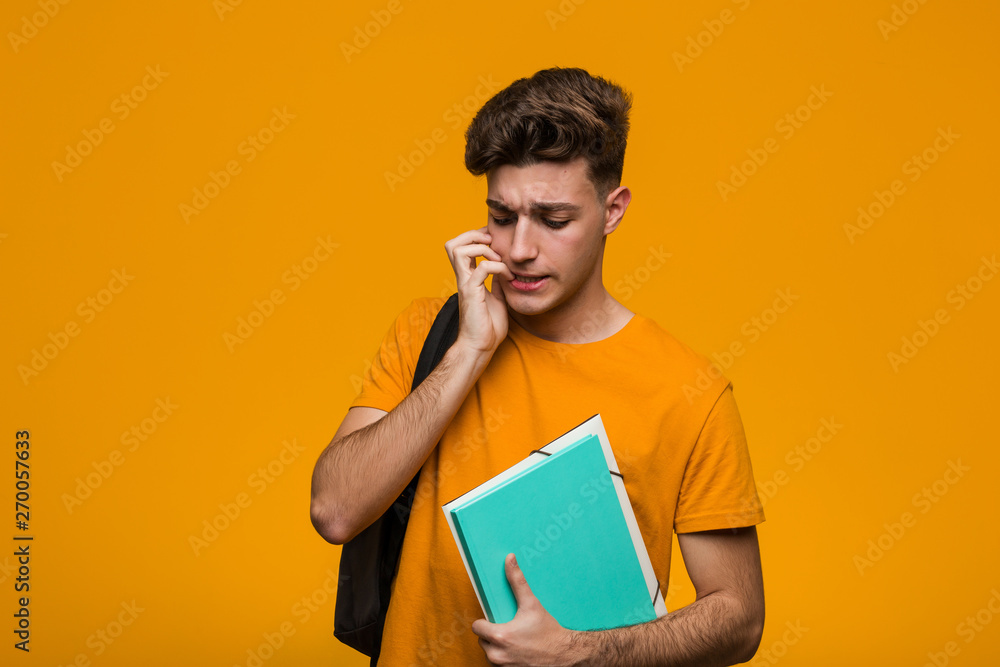 Young student man holding books crossing fingers for having luck Young student man holding books crossing fingers for having luck