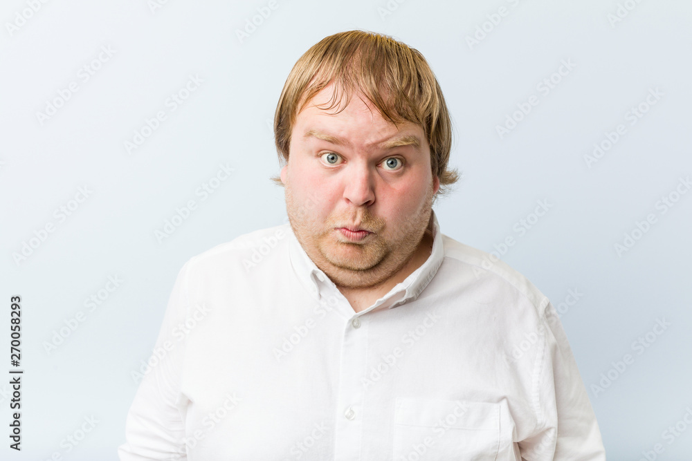 Obraz premium Young authentic redhead fat man shrugs shoulders and open eyes confused.