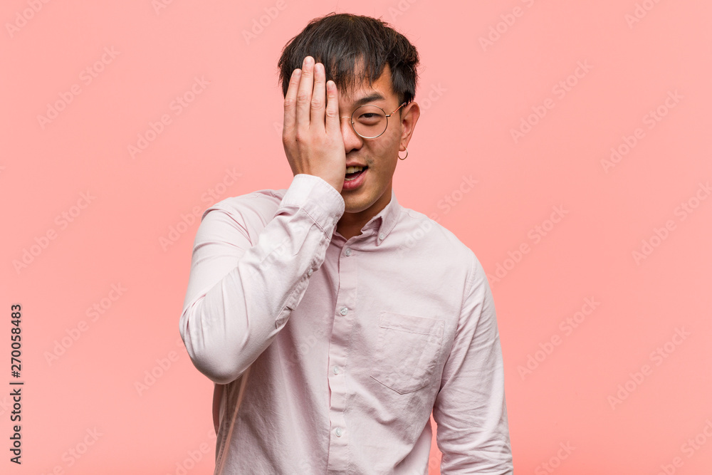 Young chinese man shouting happy and covering face with hand Young chinese man shouting happy and covering face with hand
