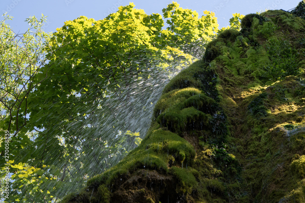 Close up shot of water drops waterfall, moss covered stone, crystal clean, nature background