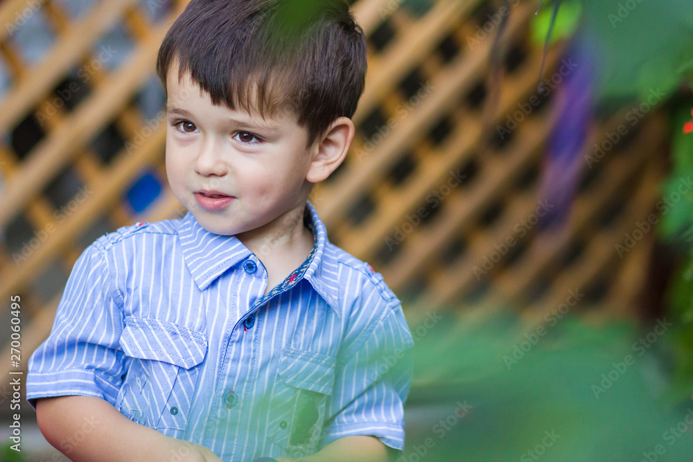 Little boy in blue and white checkered shirt smiling. Garden, outdoor activity Little boy in blue and white checkered shirt smiling. Garden, outdoor activity