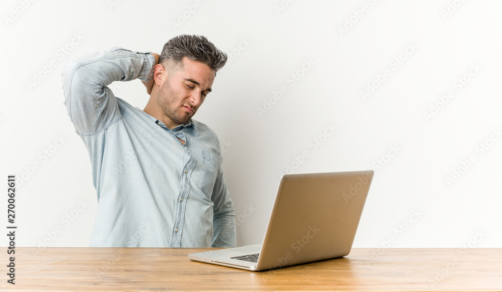 Young handsome man working with his laptop touching back of head, thinking and making a choice. Young handsome man working with his laptop touching back of head, thinking and making a choice.