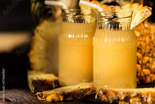 Pineapple juice and slice placed on a wooden table photo