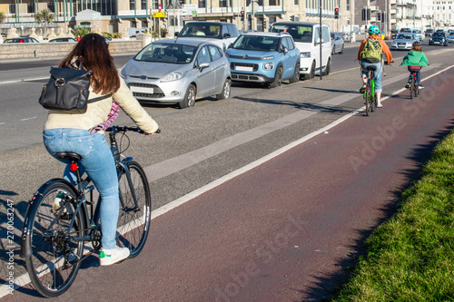 People cycling on a cycle path next to cars