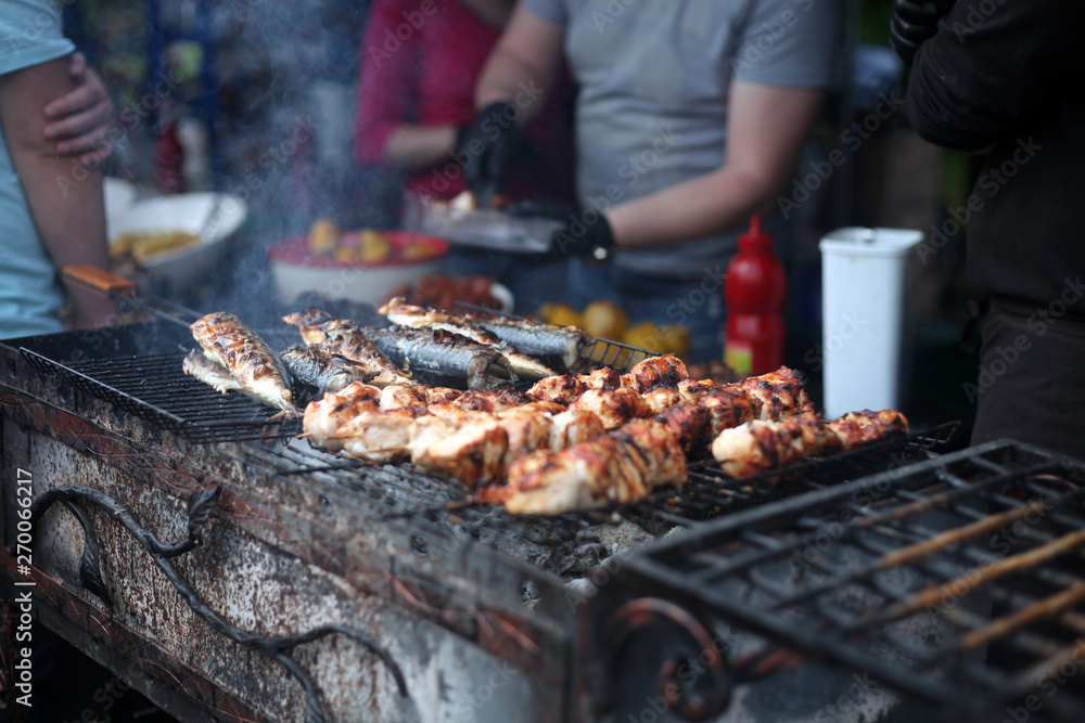 Grilled meat and fish cooked in the street food festival. Selective focus.